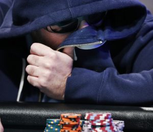 Zvi Stern covers his face with his sweatshirt while playing at the World Series of Poker main event Tuesday, July 14, 2015, in Las Vegas. The last nine players will claim at least $1 million each and a spot at the final table. (AP Photo/John Locher)